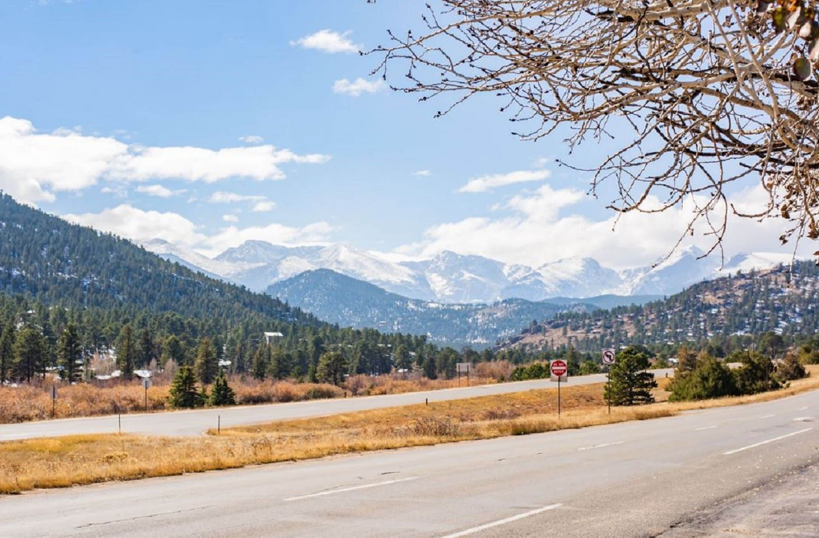 A road with a stop sign and a view of snow-capped mountains in the background.