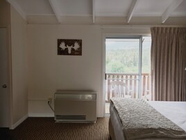 Un dormitorio con cama, un radiador, una ventana con cortinas y vistas a la vegetación exterior.