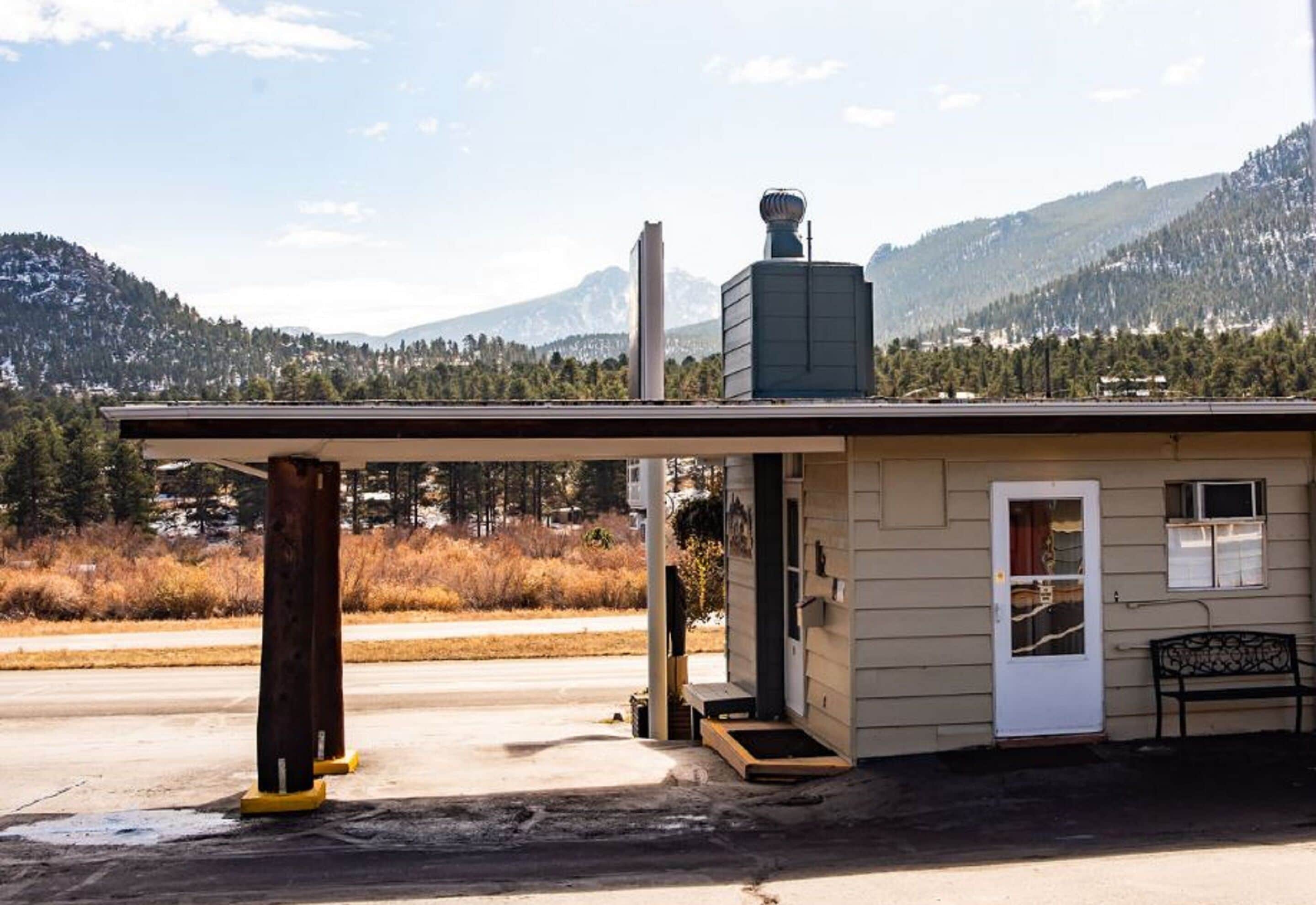 A small building with a covered entrance, a door, and a bench outside.