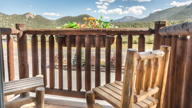 A wooden balcony with a view of a mountainous landscape. - Alpine Trail Ridge Inn (Estes Park)