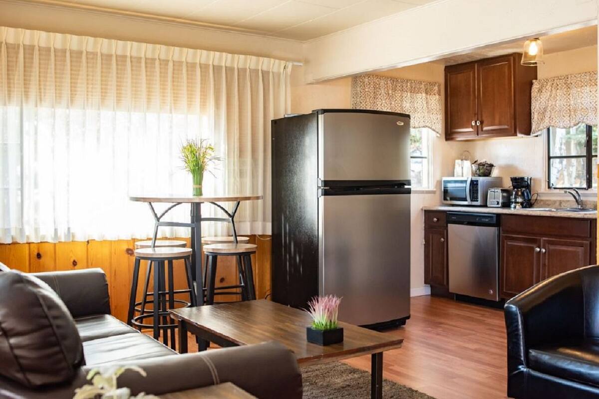 A compact kitchen with a refrigerator, microwave, and dishwasher. There is a dining area with a table and two chairs.