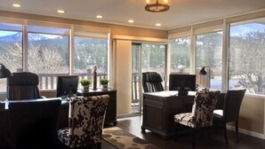 A spacious room with large windows, a desk, and two chairs. - Alpine Trail Ridge Inn (Estes Park)