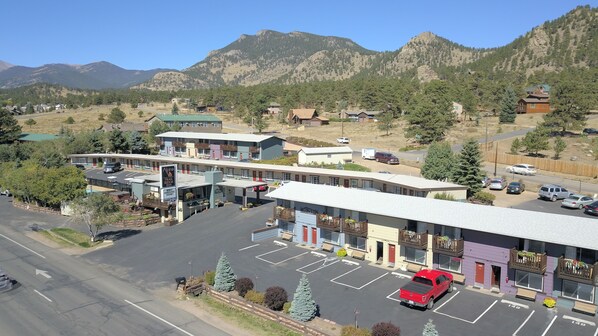 A motel with a parking lot, a red pickup truck, and a mountainous backdrop.