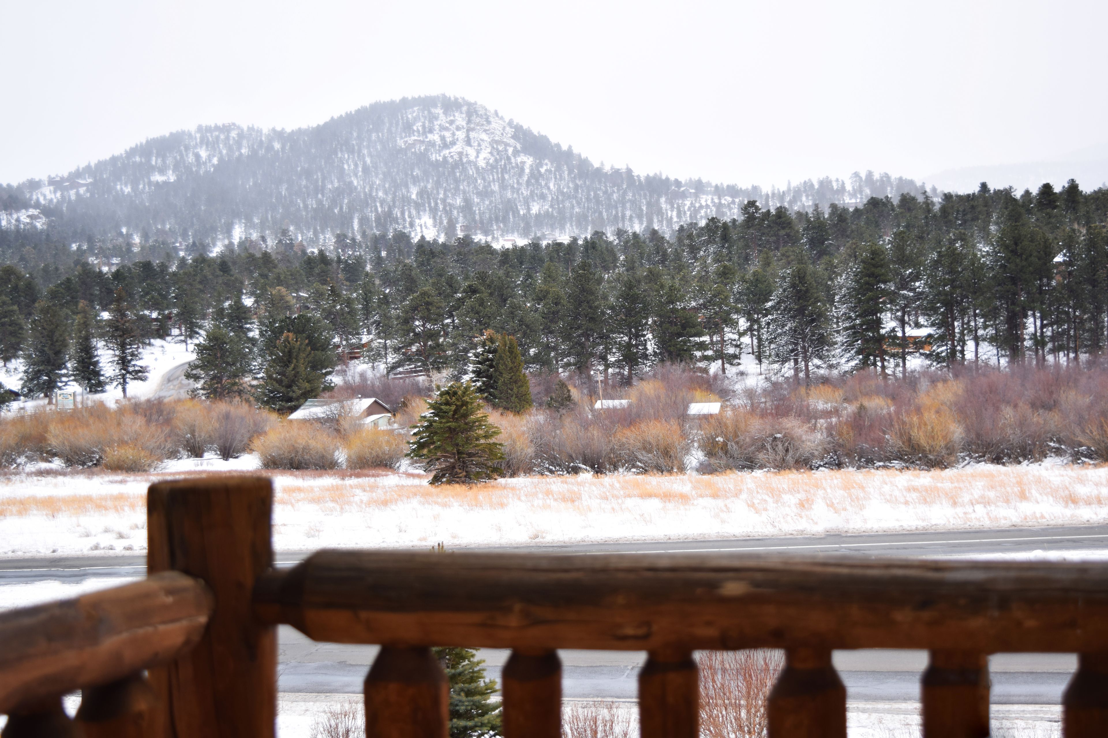 A wooden bench overlooking a snowy landscape with a mountain in the background.