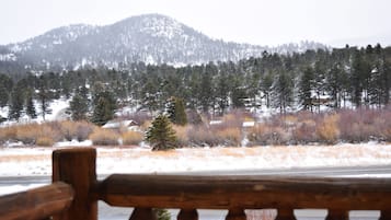 A wooden bench overlooking a snowy landscape with a mountain in the background.