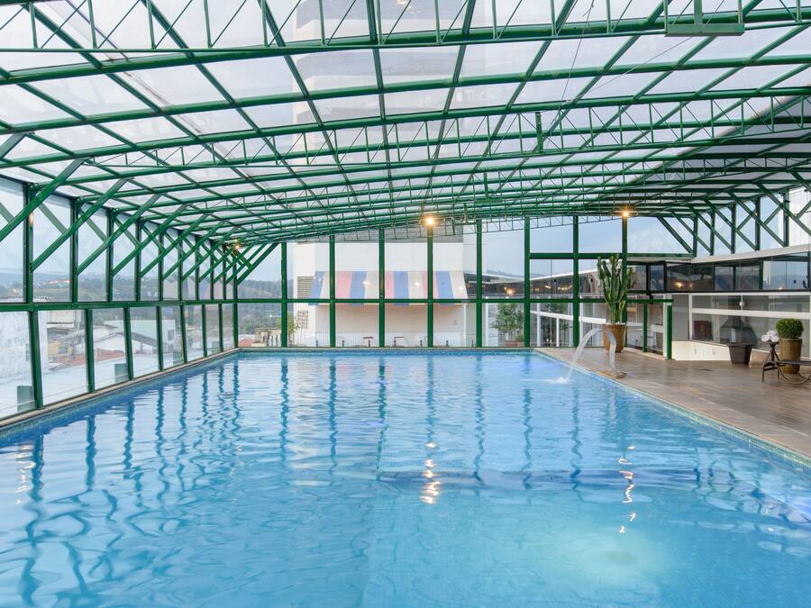 An indoor swimming pool with a glass ceiling and a view of the cityscape.