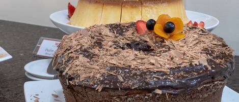 Un pastel de chocolate con fruta y virutas de chocolate sobre un plato blanco.