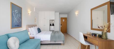 A bedroom with a bed, a desk, a chair, a sofa, and a wardrobe.
