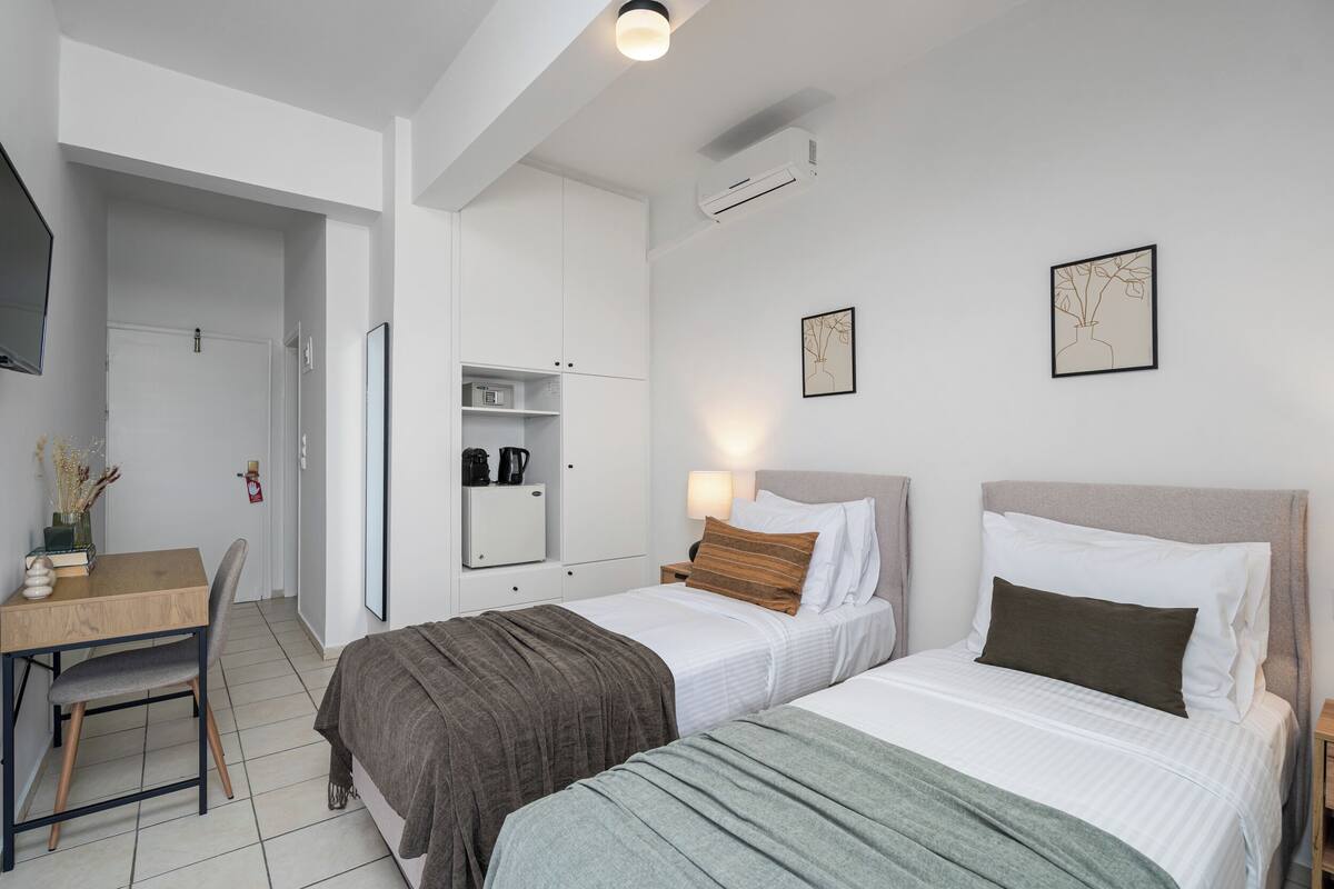 Un dormitorio con dos camas, un escritorio, una silla, un armario y una mesita de noche.