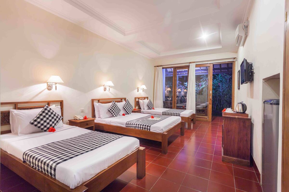 A hotel room with two beds, a TV, a minibar, and a sliding glass door to the outside.