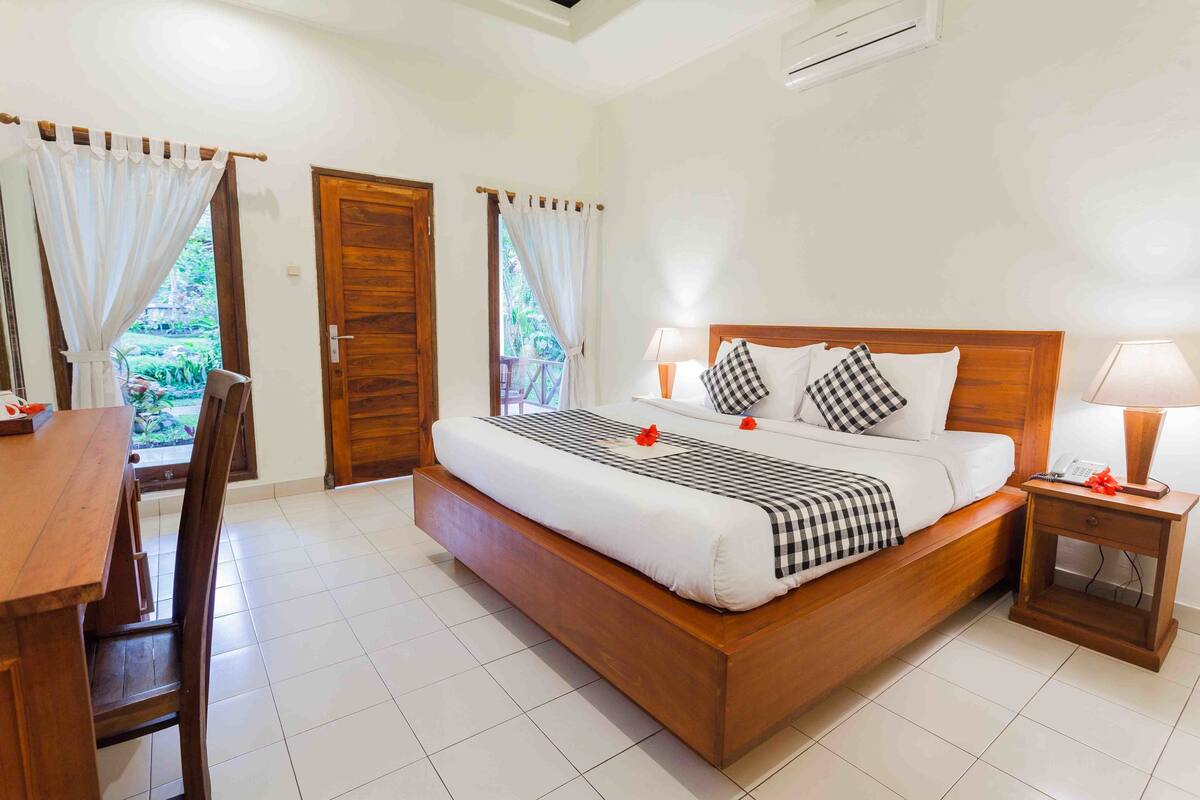 A neatly arranged bedroom with a wooden bed, bedside tables, a chair, and a dining table.