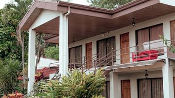 A two-story building with a balcony, wooden doors, and a staircase.
