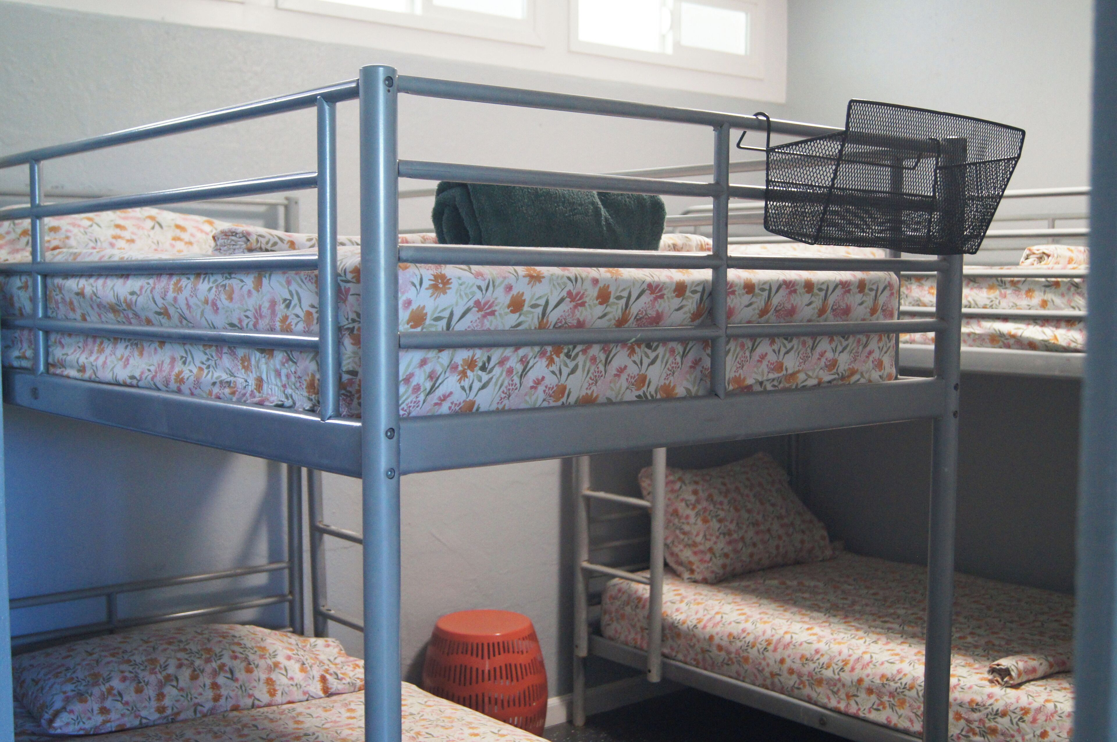 A bunk bed with floral bedding and a black metal basket on the top bunk.