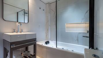 Un baño moderno con un espejo grande, dos lavamanos, una bañera y una ducha con mampara de vidrio.