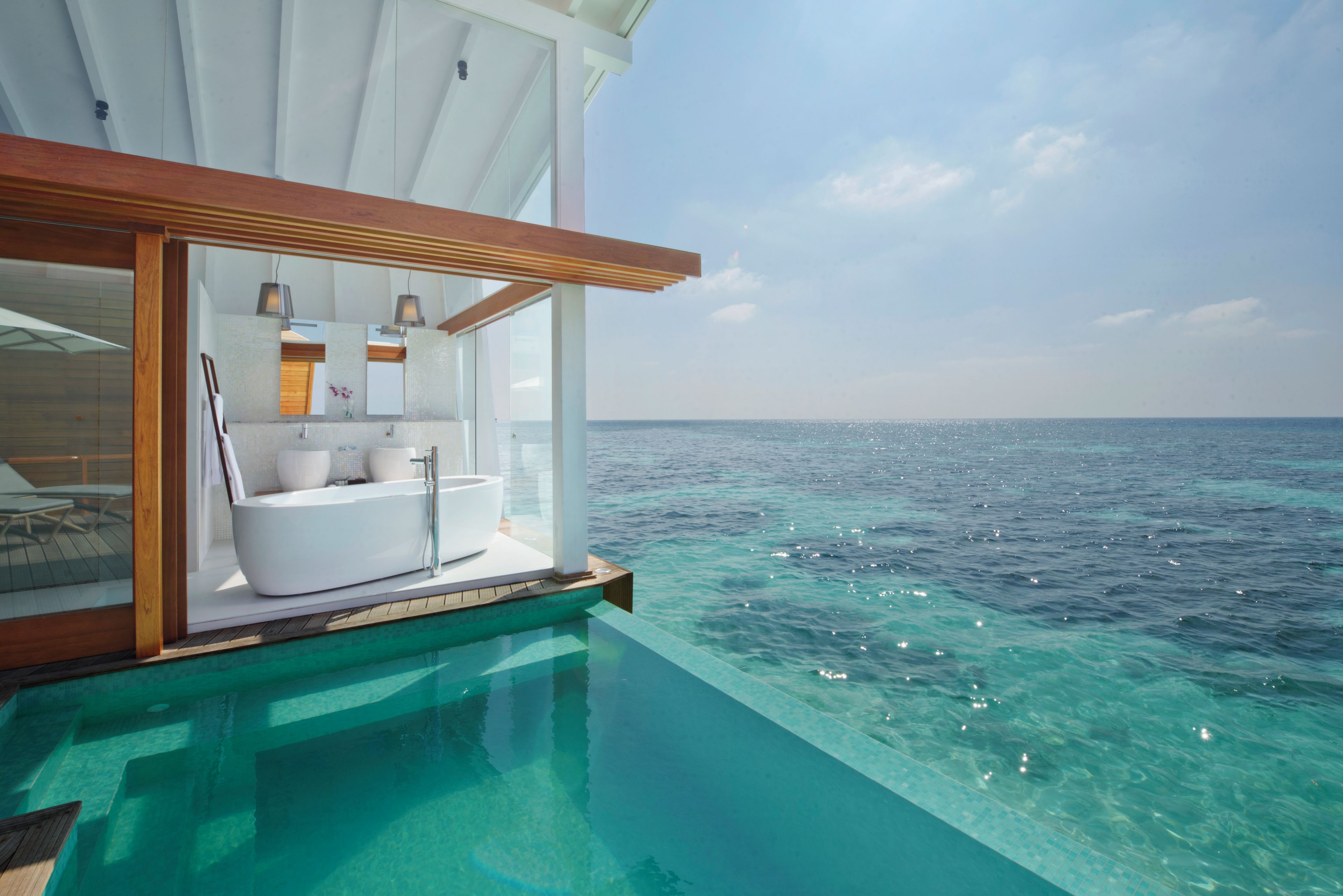 Una piscina infinita con baño privado que incluye bañera, lavamanos y tocador.