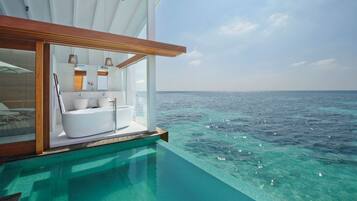Una piscina infinita con baño privado que incluye bañera, lavamanos y tocador.