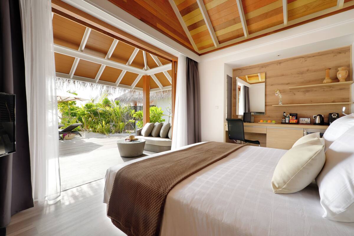Un dormitorio con una cama grande, un escritorio y vista a un jardín.