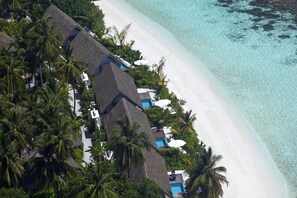 An aerial view of a resort with thatched-roof buildings, a white sandy beach, and clear turquoise waters. - Kandolhu Maldives (NORTH ARI ATOLL)