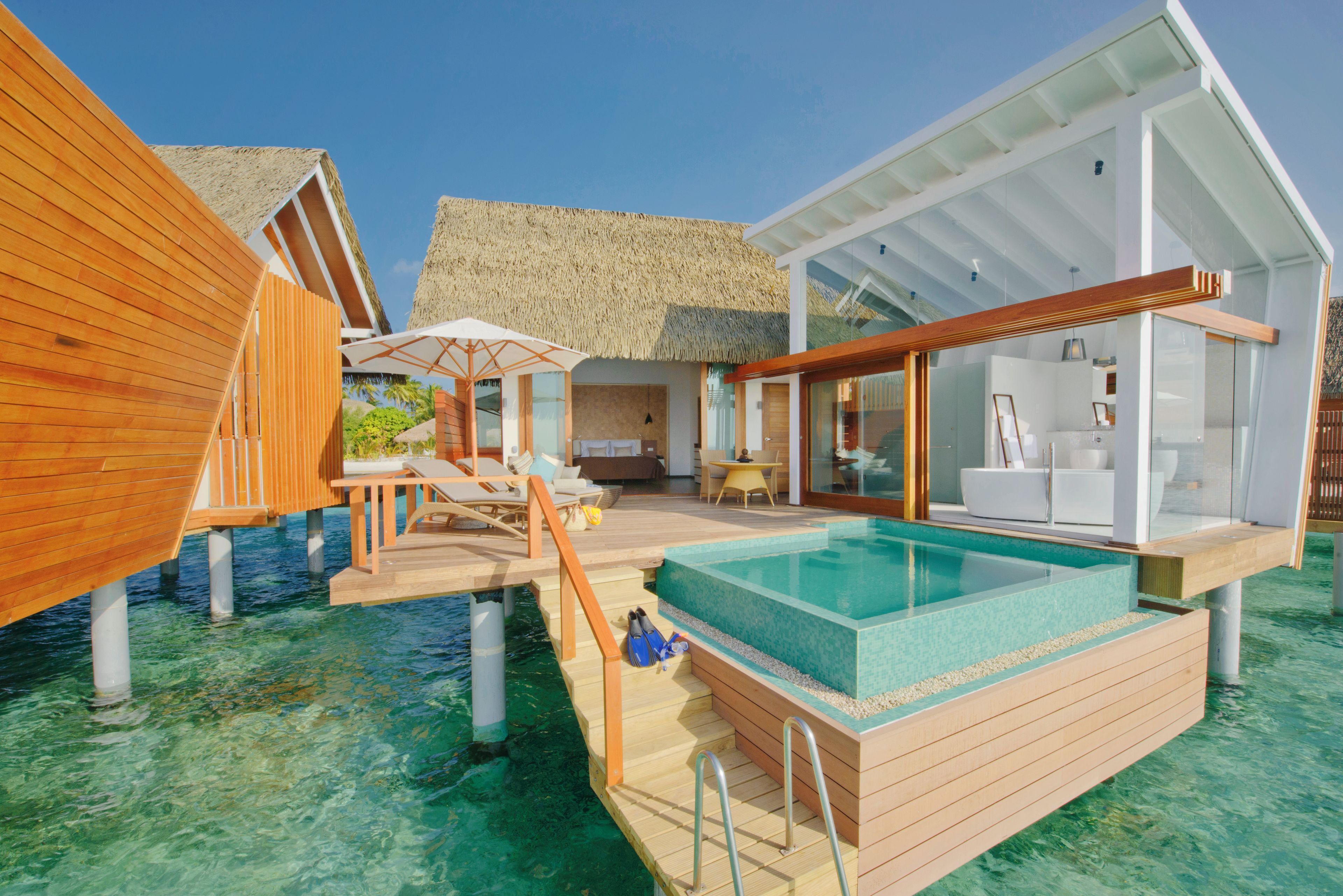 An overwater bungalow with a private pool, wooden deck, and thatched-roof structure.