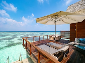 A wooden deck with lounge chairs and a table, overlooking turquoise waters and a clear sky. - Kandolhu Maldives (NORTH ARI ATOLL)