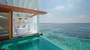 Una piscina infinita con vistas al océano, un baño moderno con bañera y una terraza de madera.