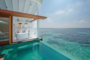 An infinity pool with a view of the ocean, a modern bathroom with a bathtub, and a wooden deck. - Kandolhu Maldives (NORTH ARI ATOLL)