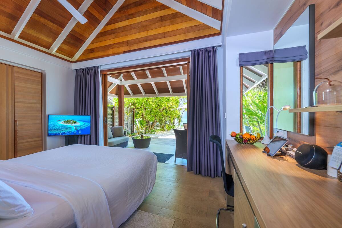 Un dormitorio con una cama, un televisor, un escritorio con ordenador y vistas al exterior.