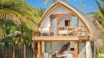 Una casa de dos pisos con piscina, rodeada de palmeras.