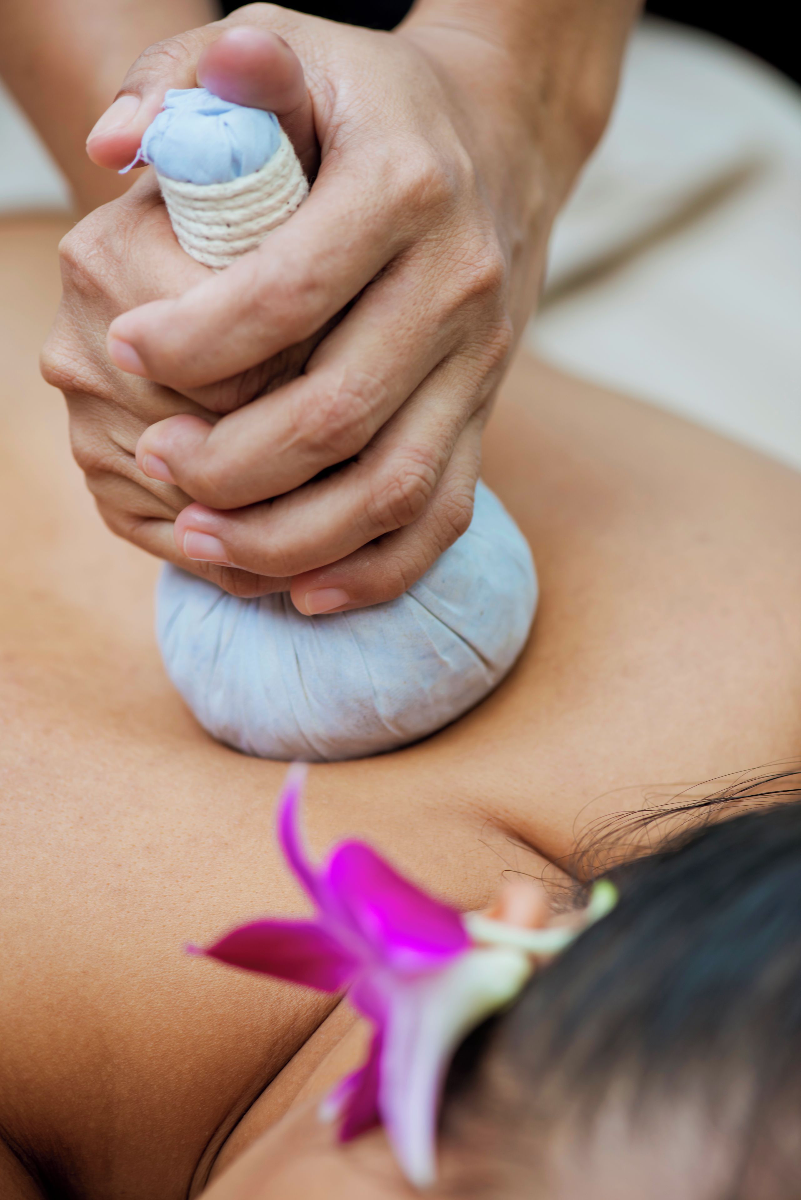 A close-up of hands applying a massage tool to a person's back.