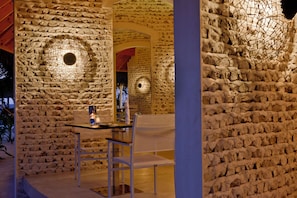 Un espace de restauration en plein air avec des murs en pierre et des luminaires circulaires.