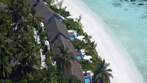 An aerial view of a resort with thatched-roof buildings, a white sandy beach, and clear turquoise waters. - Kandolhu Maldives (NORTH ARI ATOLL)
