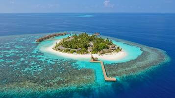 An aerial view of a tropical island resort with overwater bungalows, a central island with a gazebo, and a clear blue sea.