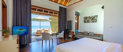 Una camera d'hotel moderna con un letto grande, una scrivania con sedia, una TV e vista sull'oceano.