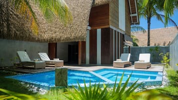 Un área de piscina con sillas de descanso y una estructura de techo de paja.