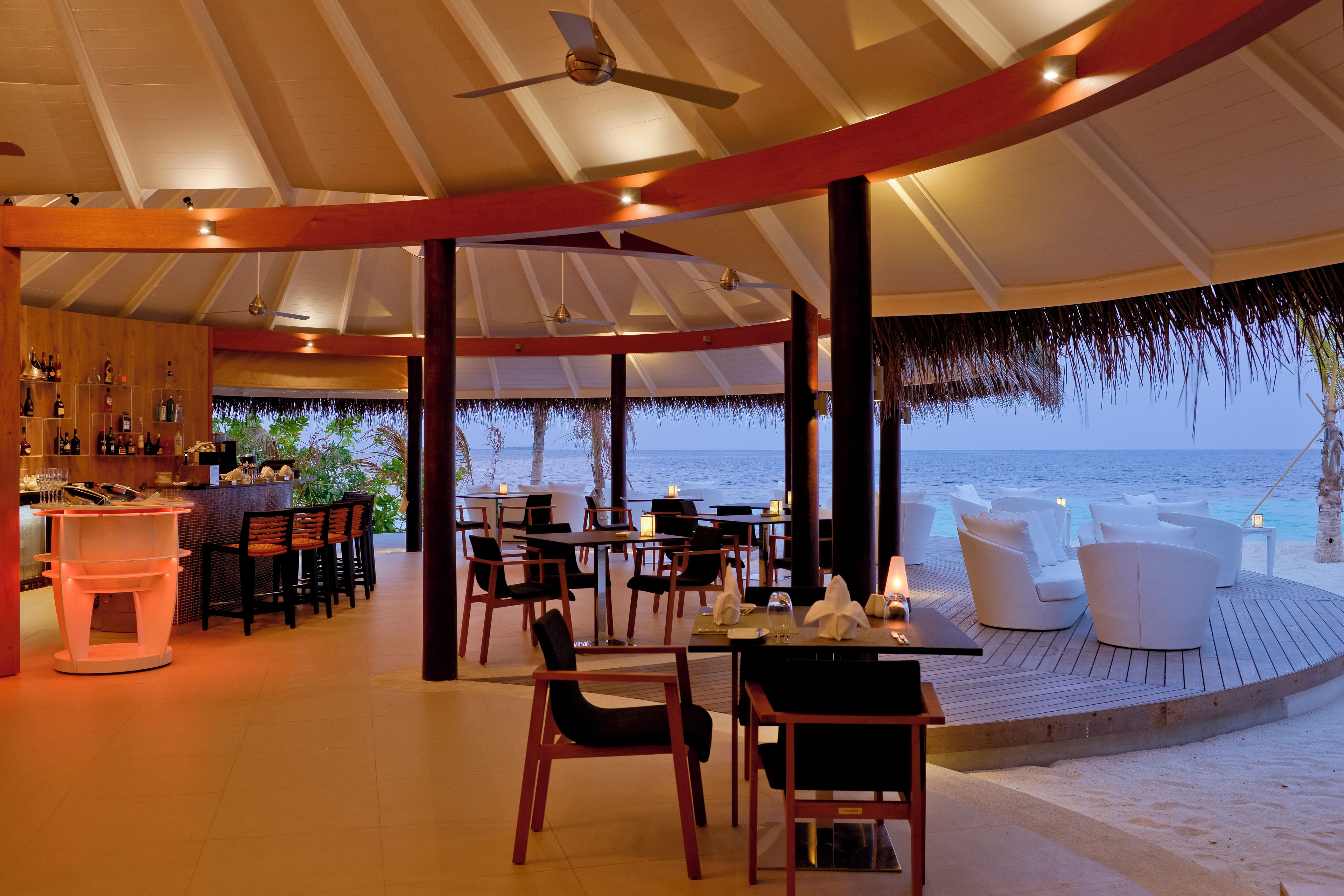Un restaurante frente al mar, con vistas al océano, mesas, sillas y una zona de bar.