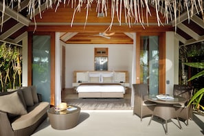 A modern bedroom with a large bed, a ceiling fan, and a glass door leading to a balcony. - Kandolhu Maldives (NORTH ARI ATOLL)
