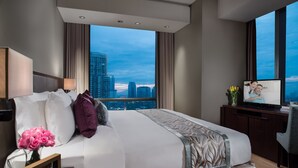 A modern hotel room with a large bed, a desk, a chair, and a view of the cityscape. - Ascott Kuningan Jakarta (Jakarta)