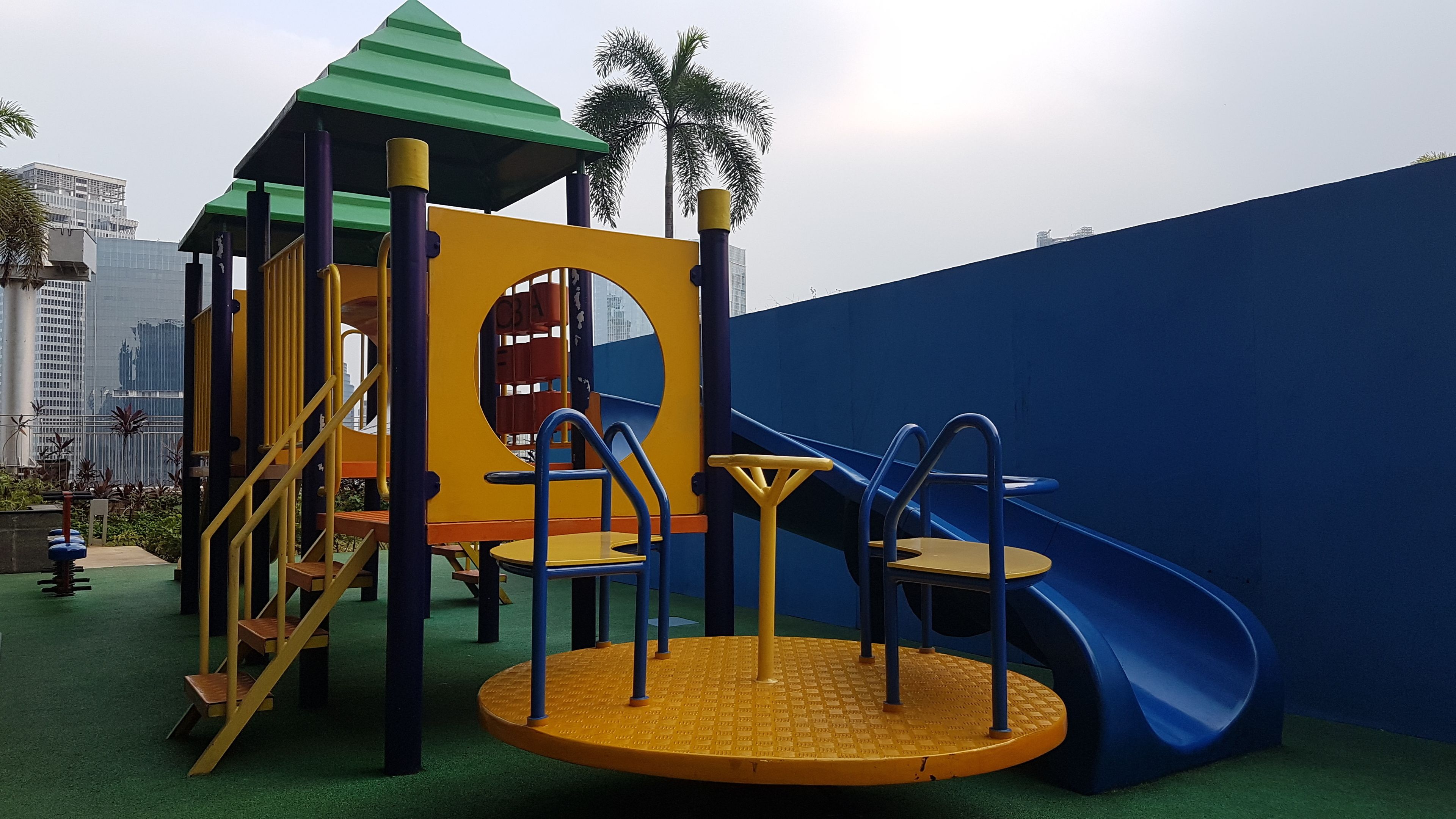 A playground with a slide, climbing structures, and a circular play area.