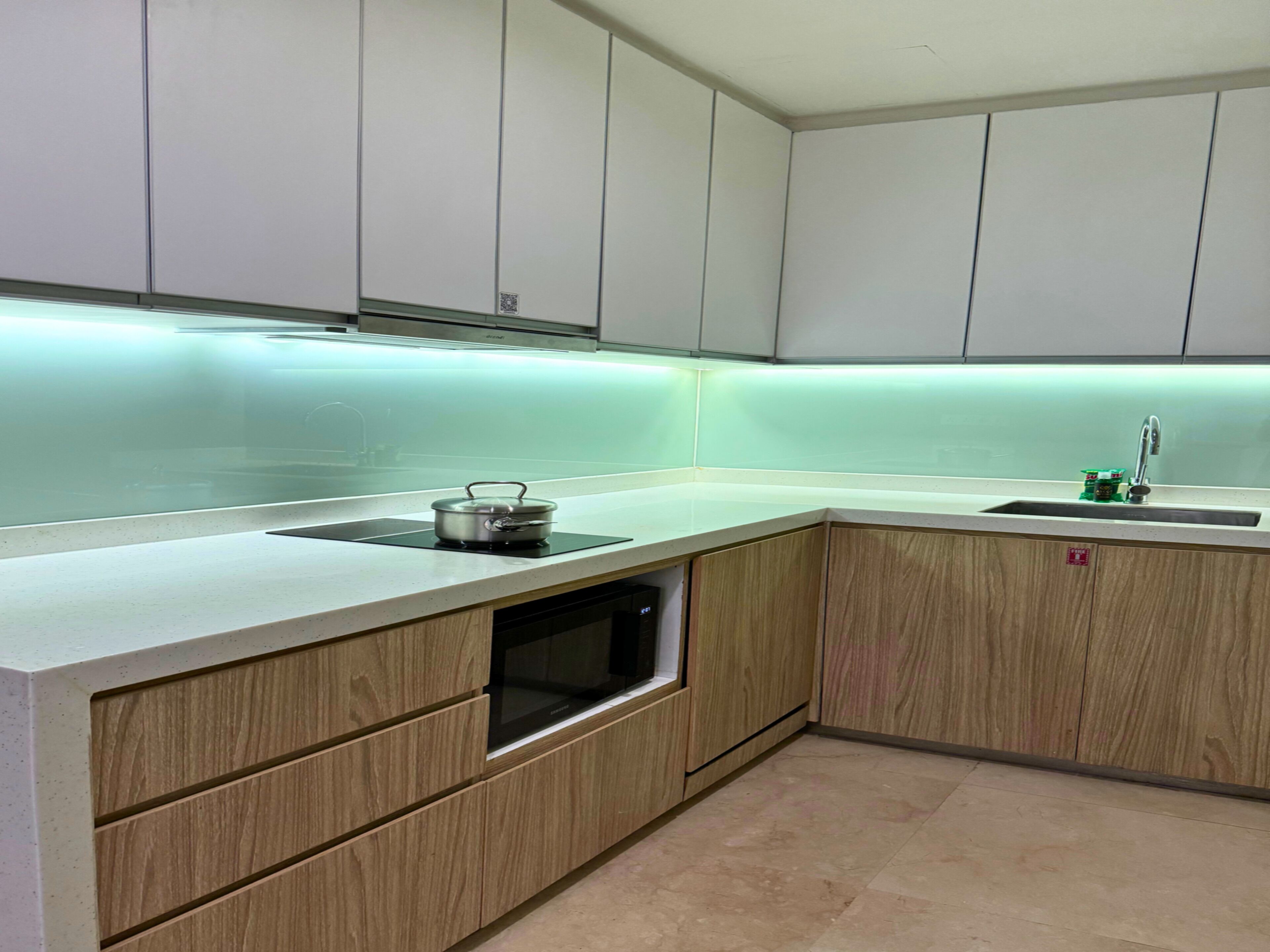A modern kitchen with white cabinets, a built-in oven, and a stainless steel sink.