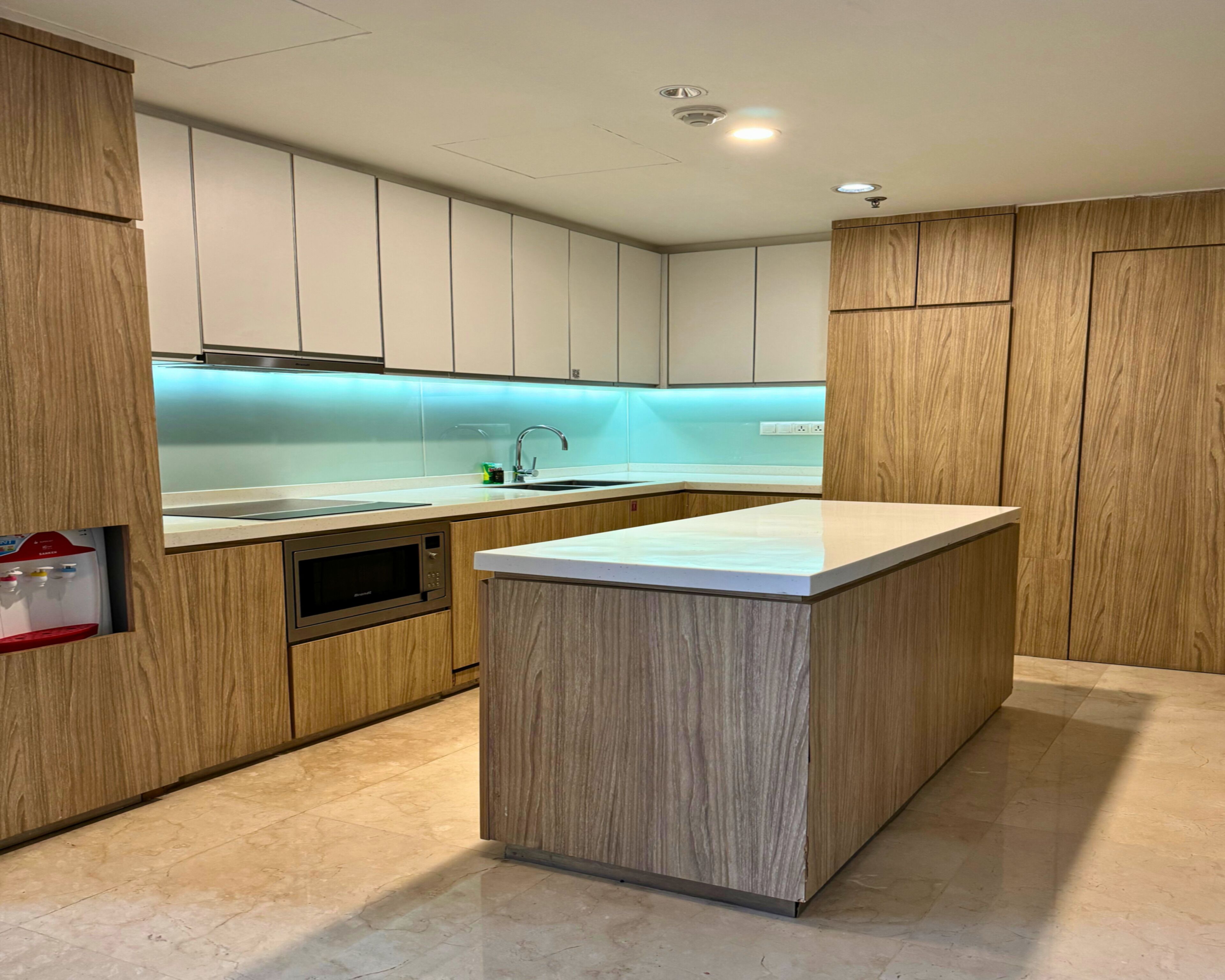 A modern kitchen with wooden cabinets, a built-in microwave, and a countertop island.