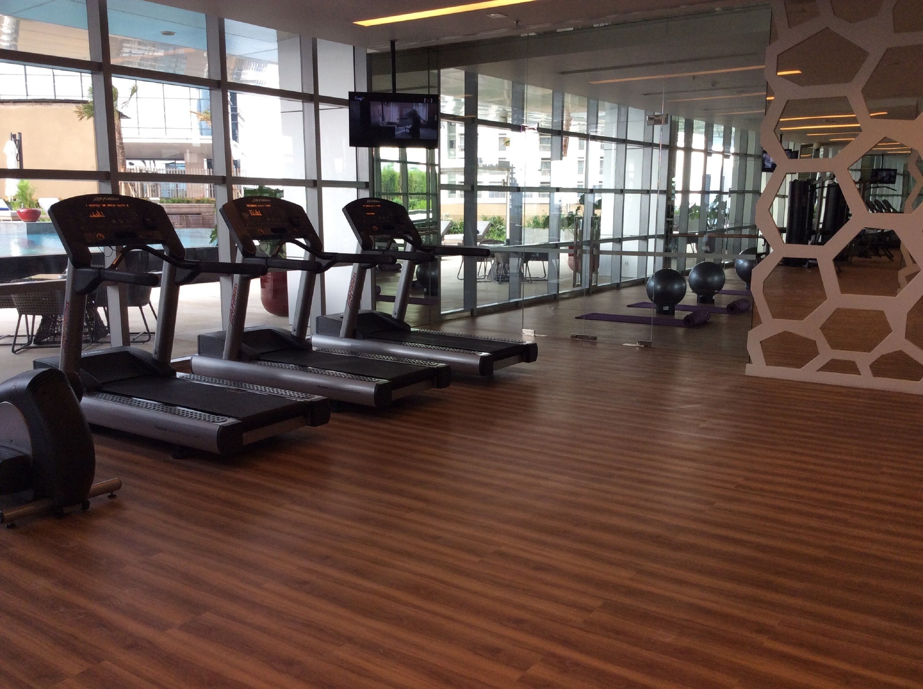 Une salle de sport équipée de tapis de course, de ballons d’exercice et d’un écran de télévision.