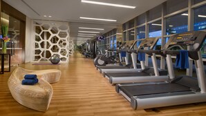 A gym with treadmills, a wooden floor, and large windows. - Ascott Kuningan Jakarta (Jakarta)
