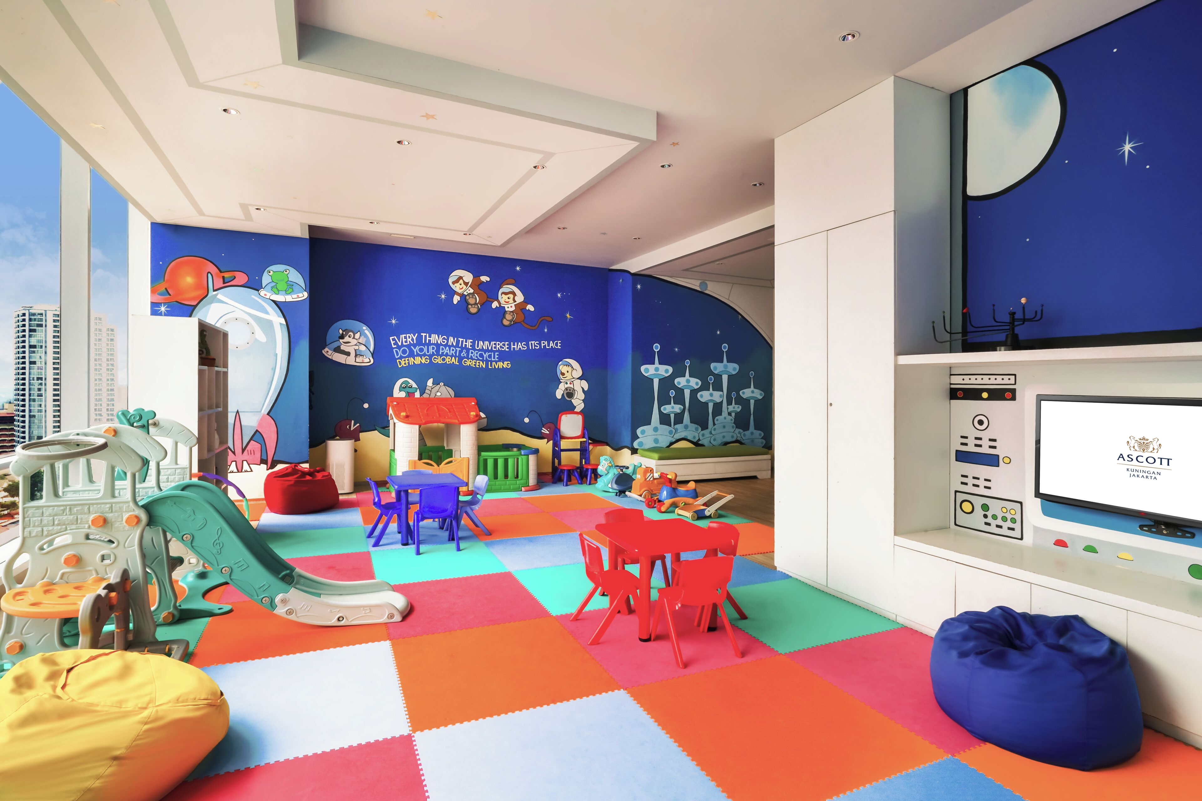 A children's play area with colorful flooring, play furniture, and educational wall murals.
