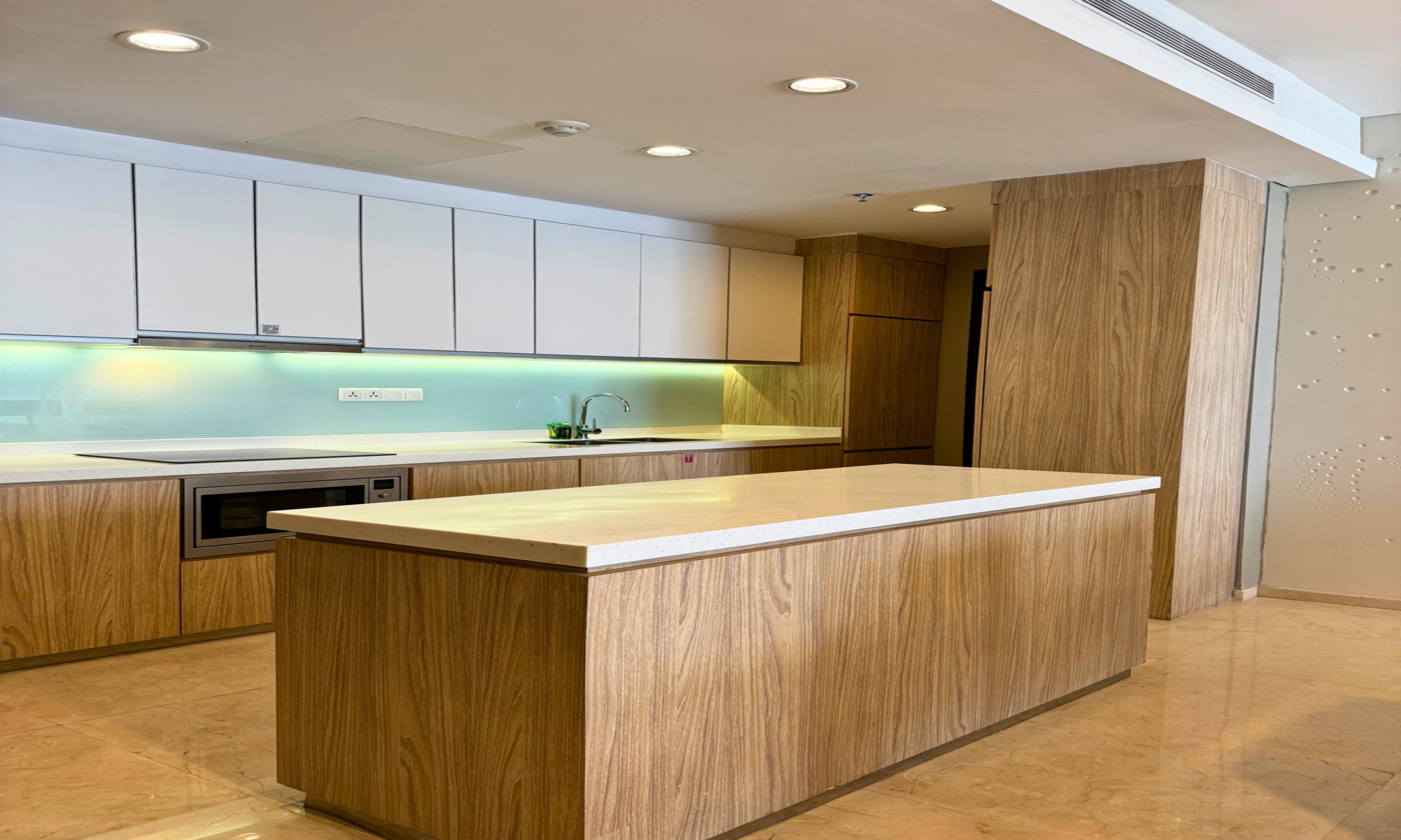 A modern kitchen with wooden cabinetry, a central island, and recessed lighting.