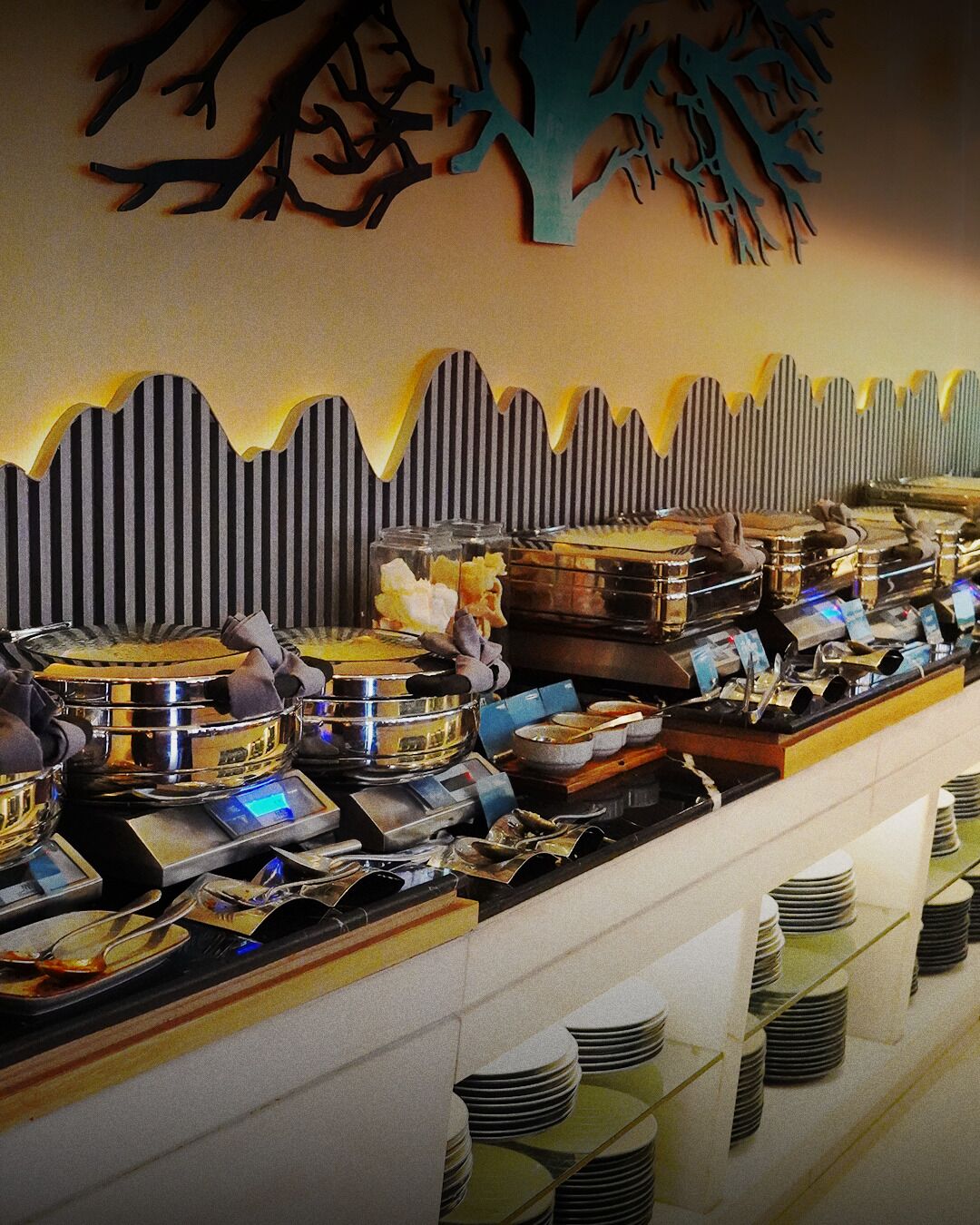 Una barra de buffet con diferentes recipientes de comida y utensilios.
