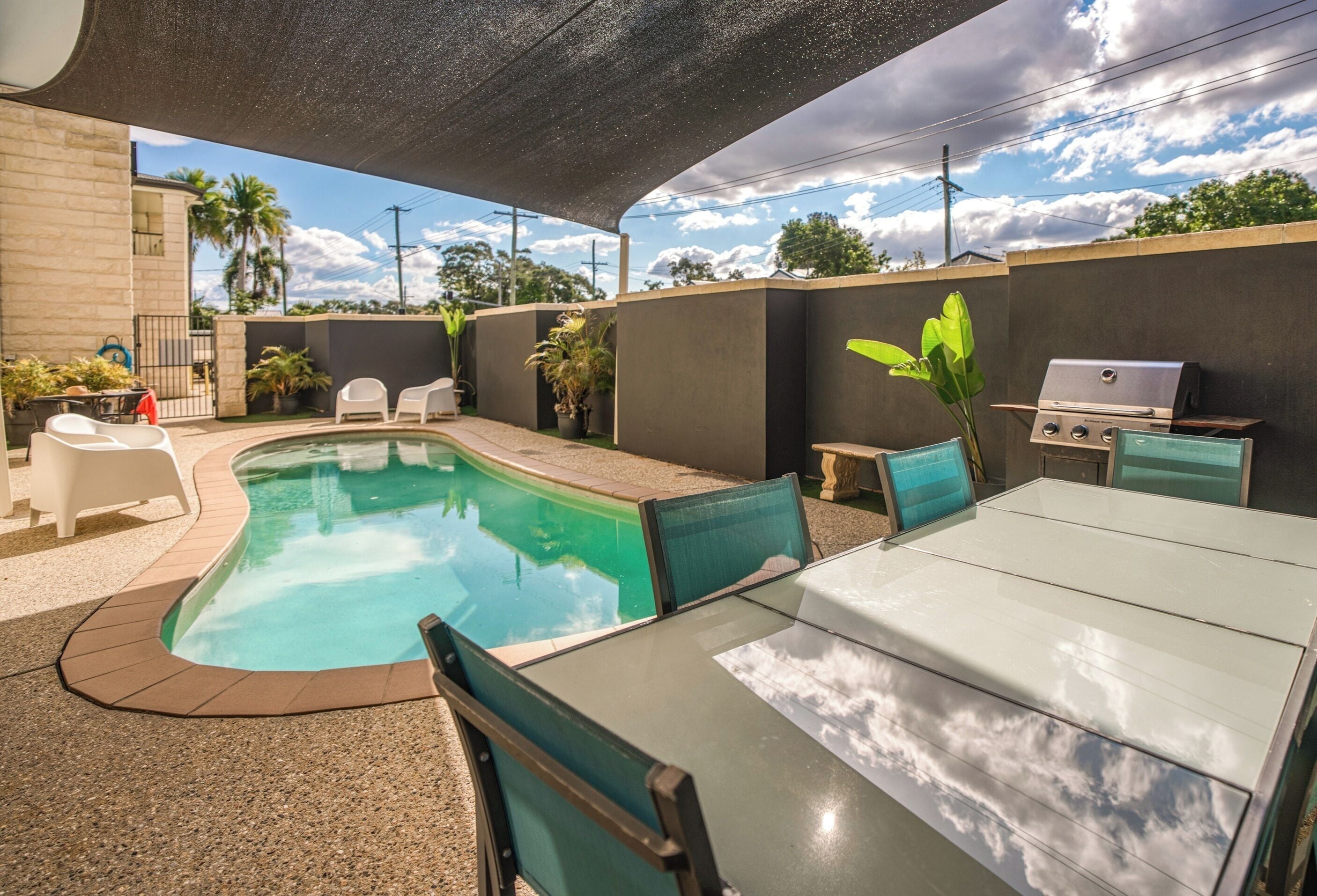 Un espace piscine doté d’un plafond incurvé, d’un coin salon extérieur et d’un barbecue.