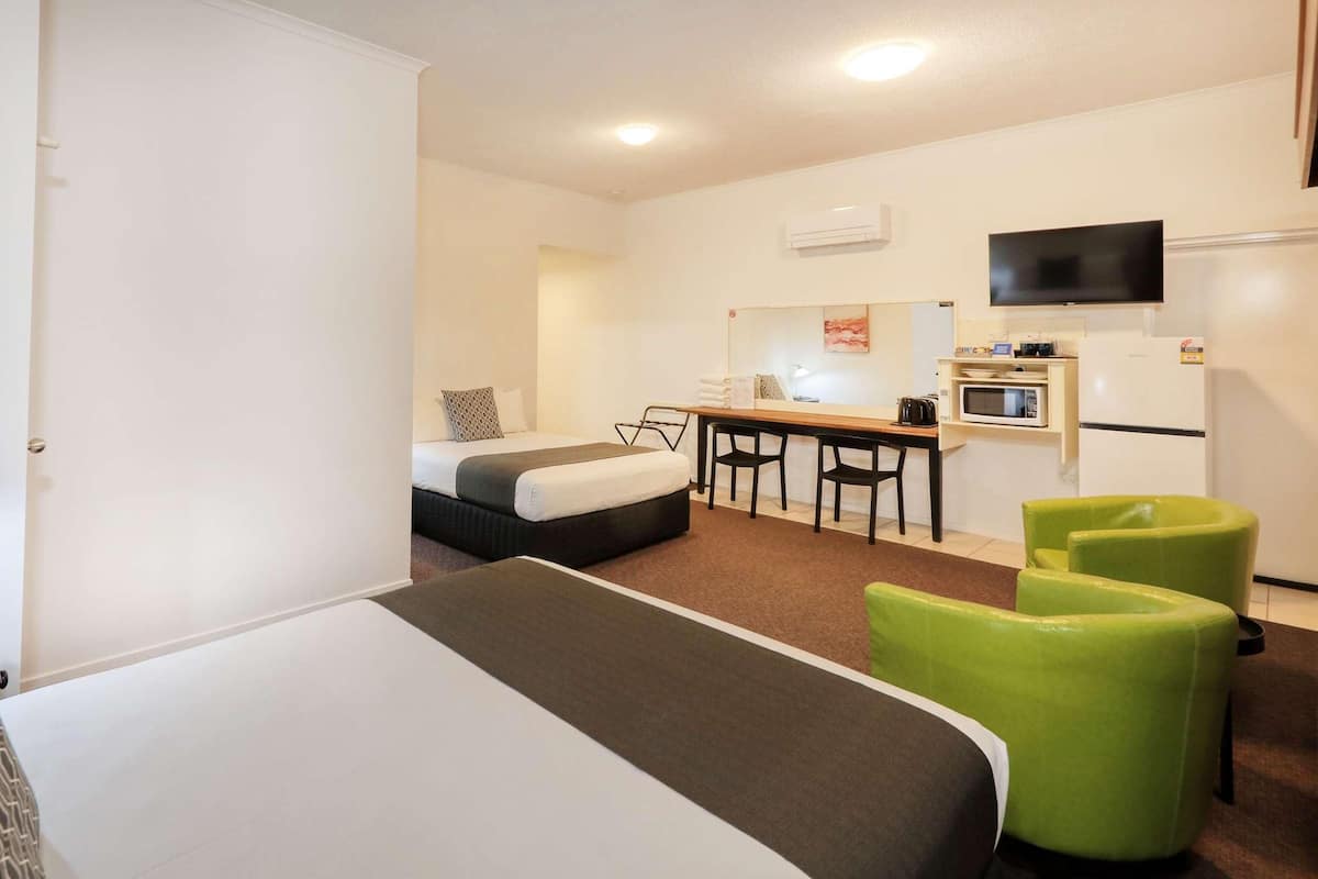 A hotel room with a bed, a desk, a chair, a microwave, and a TV.