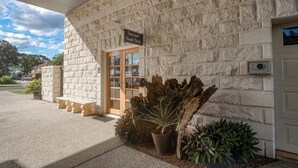 A stone building with a reception desk, a sign reading 'Save and Book Direct,' and a security keypad. - Caboolture Gateway Motel (Caboolture)