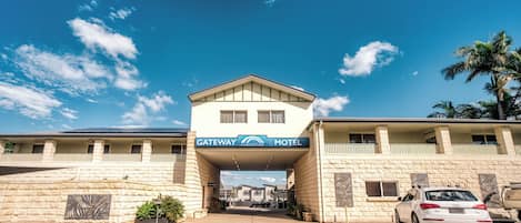 A Gateway Motel with a clear sky, a car parked in front, and a palm tree to the right.