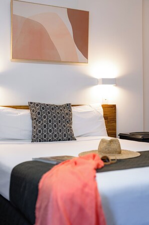 A hotel room with a bed, a bedside lamp, a wall-mounted abstract painting, and a nightstand with a telephone. - Caboolture Gateway Motel (Caboolture)